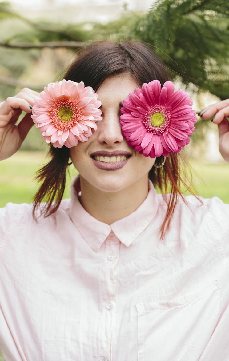 young woman covering eyes flowers smiling